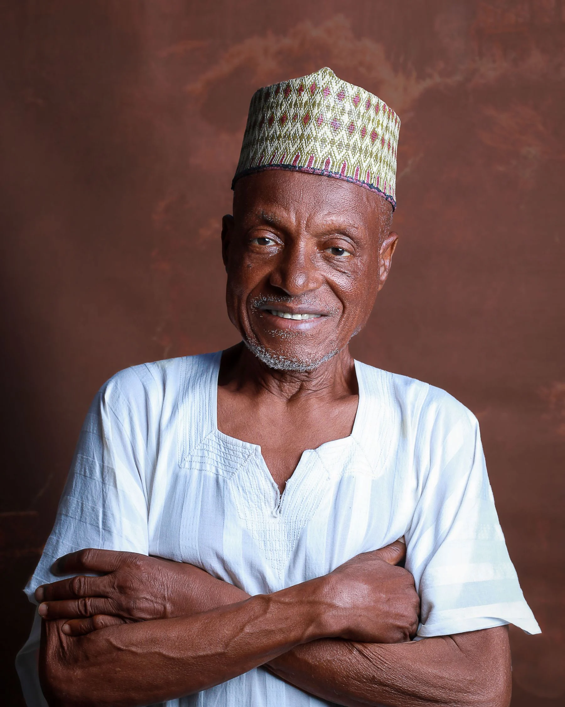 Real portrait of an older Nigerian man in a white kaftan and patterned cap